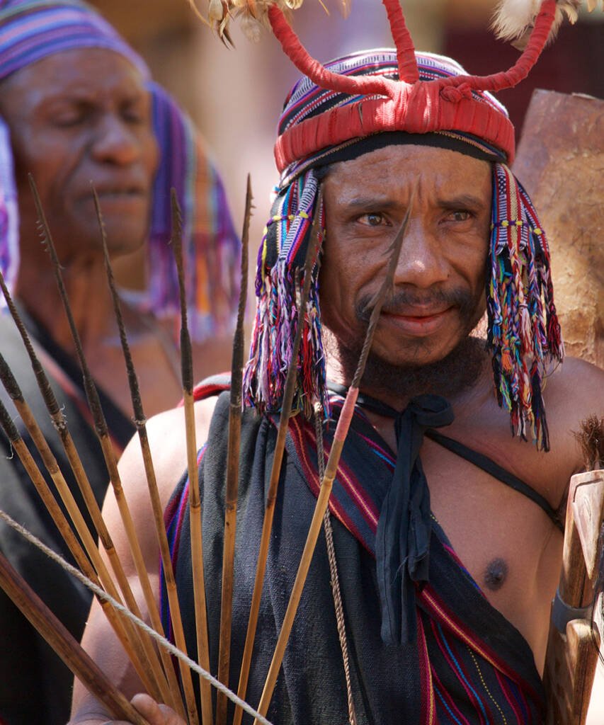 Man in a traditional red headdress and beaded strands, Eastern Indonesia