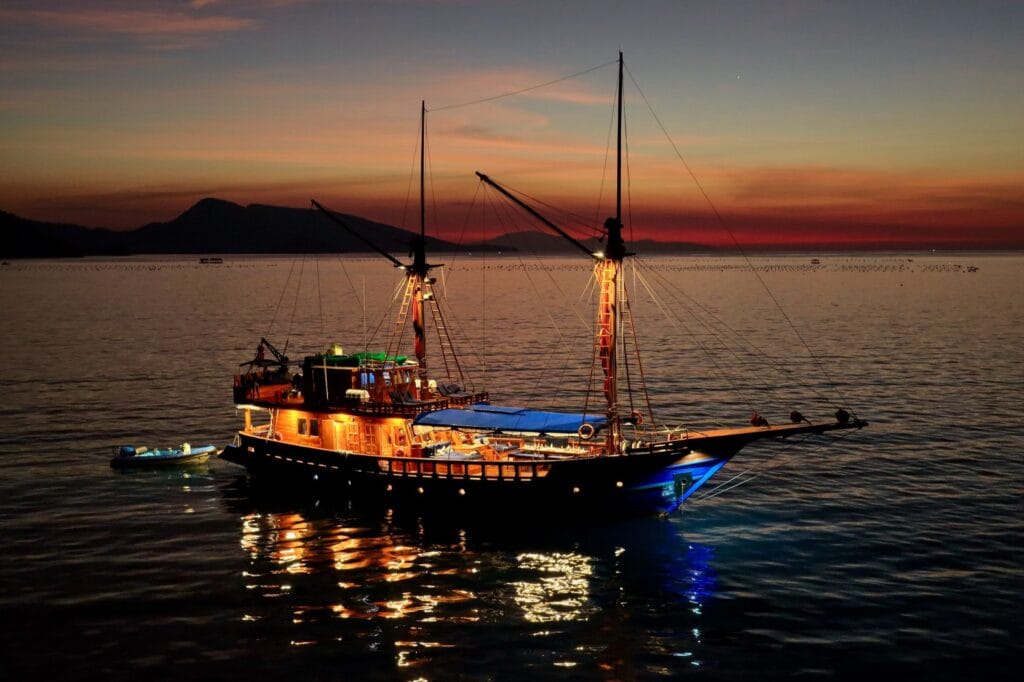 Tiger Blue at anchor at dusk with her deck lights on, seen from the air
