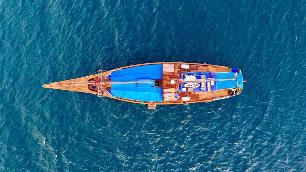 Tiger Blue at anchor over a shallow turquoise reef, seen from above