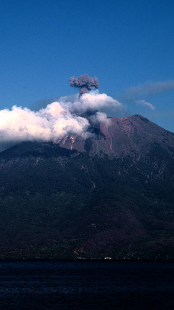 Smoking volcano rising above the sea in Eastern Indonesia