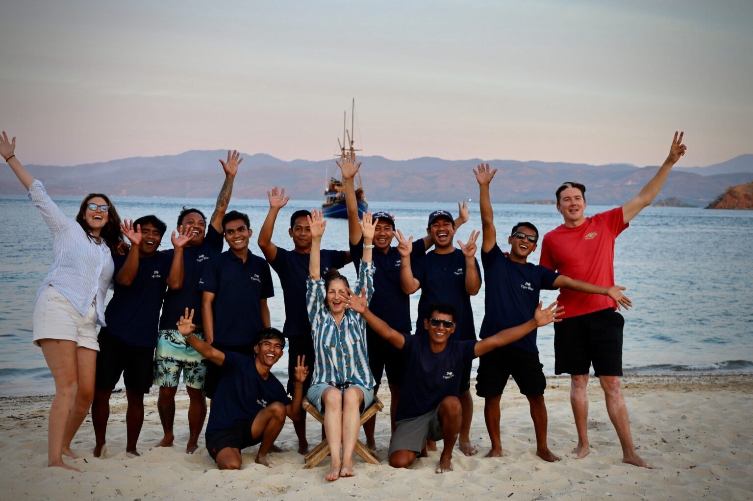 The Tiger Blue crew cheering on a beach with the boat behind