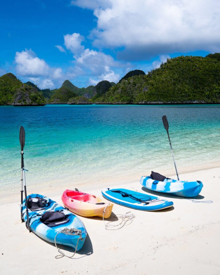 Kayaks and paddle boards on a white-sand beach in Raja Ampat